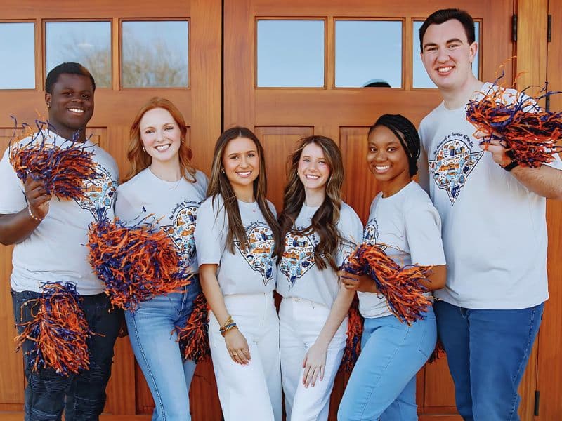 Group of smiling student with matching shirts and pom poms