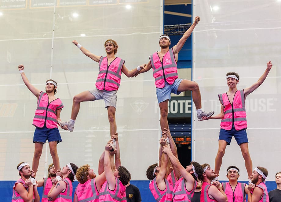 A group of students in pink vests form a human pyramid.
