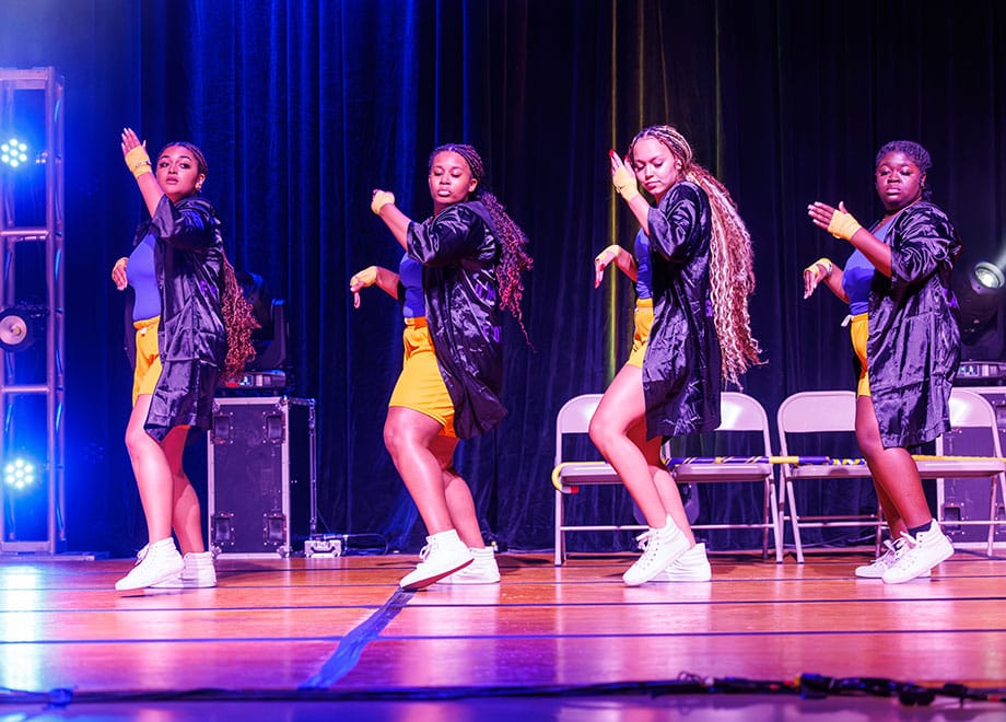 Four adults perform on stage during a step show.