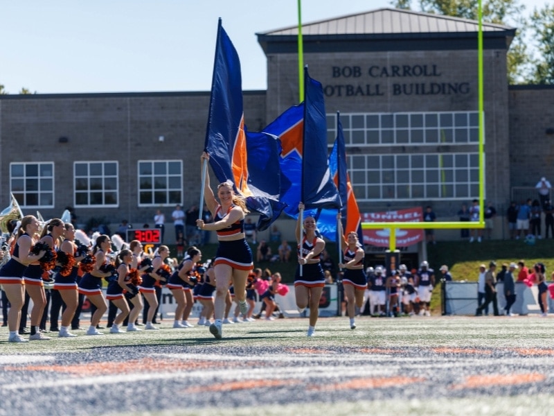 Skyhawk cheerleaders storm the field with flags.